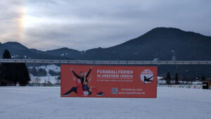 Fußballschule Hans Dorfner auf verschneitem Fußballfeld mit Bergkulisse, bietet Fußballtraining für Kinder und Jugendliche in einer winterlichen Umgebung.